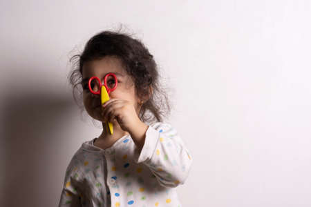 Little girl holding a small colorful scissor in front of her eyes, tailoring conceptの写真素材