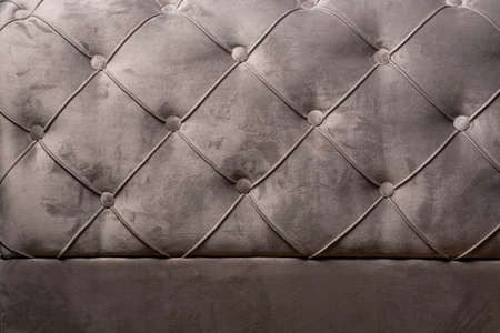 Gray velvet sofa background texture with sunken buttons, close up velvet texture
