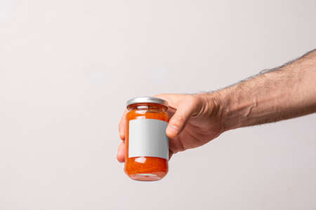 A male hand holding a juicy homemade carrot jar on a white background, editable mock-up series template ready for your design, label selection path included.の写真素材