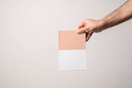 Male hand holding a closed book-catalog with blank cover, editable mock-up series template ready for your design, cover selection path included.の写真素材