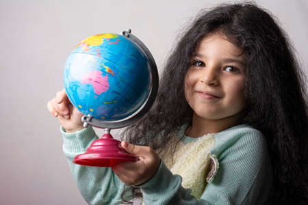Little girl portrait holding a globe in hand and spin it.の写真素材