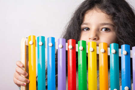 Little girl portrait with xylophone in hand looking in camera with expression, childhood memoriesの写真素材