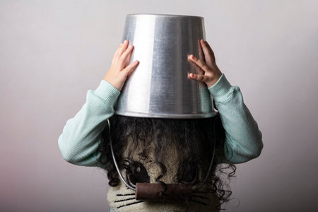 Little girl put her head inside metal bucket, childhood fun play conceptの写真素材