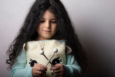 Little girl portrait with xylophone sticks in hand looking down, childhood memoriesの写真素材