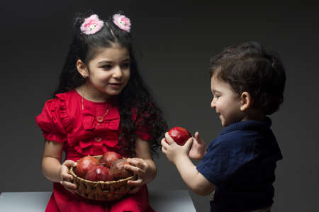 Little girl with her brother holding a pomegranates basket. family togetherness concept happy yalda Iranian celebration themeの写真素材