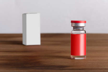 Medical vial for injection on wooden board background. Medicine and healthcare concept. editable mock-up series template ready for your design. label and box faces selection path included.の写真素材