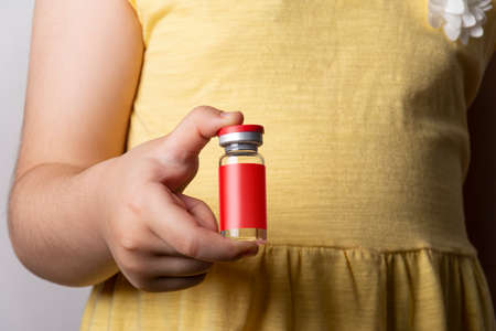 Little girl holding an injection vial in right hand. Editable mock-up series template ready for your design. label selection path included.の写真素材