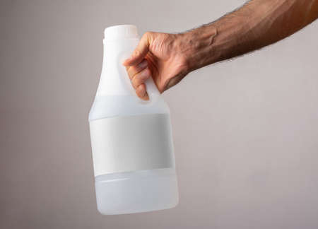 A male hand holding a vinegar bottle with blank label, mock-up series template ready for your...