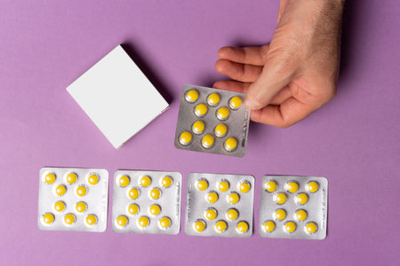Male hand holding a pills tablet in front of blue background, selection path included.