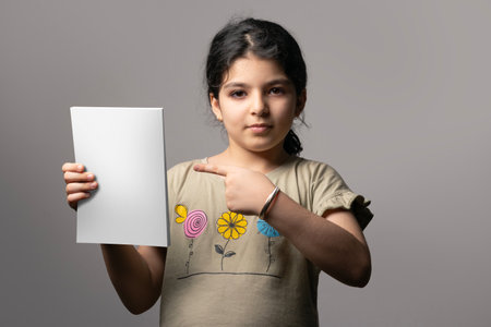 Little girl pointing a novel book with blank cover, editable PSD mock-up series with smart object layersの写真素材