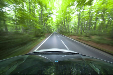 car driving fast into forestの写真素材