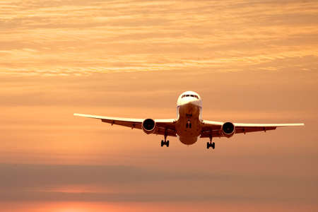 An airplane flying in the orange skyの写真素材