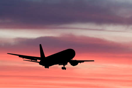 An airplane flying in the orange skyの写真素材