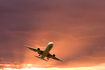 An airplane flying in the orange skyの写真素材