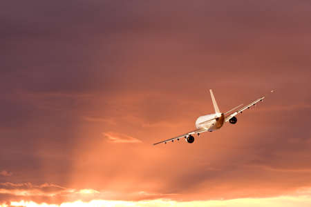 An airplane flying in the orange skyの写真素材