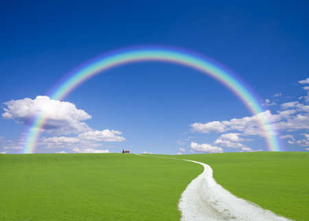 Road to red roof house with rainbowの写真素材