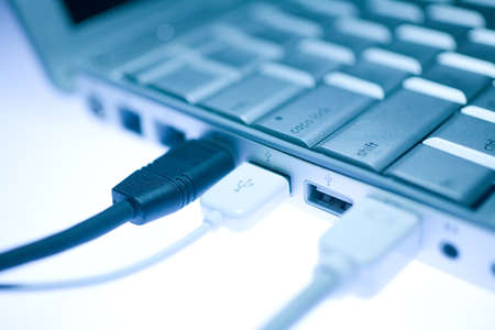USB port on the side of a laptop with an external peripheral device attachedの写真素材