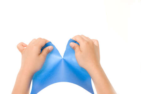 Hands tearing a precut sheet of blue paper isolated on whiteの写真素材