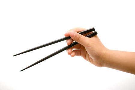 Hand holding chopsticks in the open position over whiteの写真素材