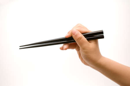 Hand holding closed chopsticks isolated on whiteの写真素材