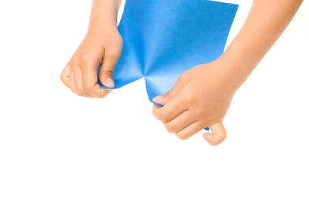 Hands tearing a sheet of blue paper over a white backgroundの写真素材