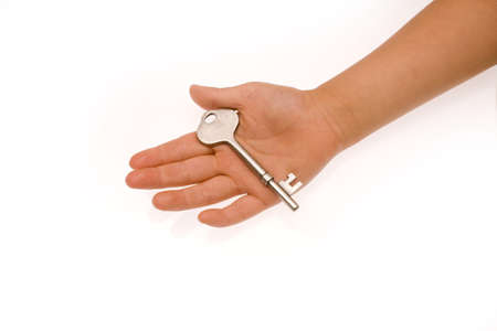 A mans hand holding a silver metal key on whiteの写真素材