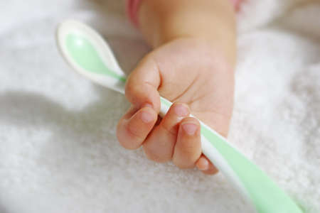 baby's hand holding a spoonの写真素材