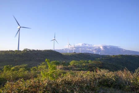 Wind turbines with a scenic snow-capped mountainの写真素材