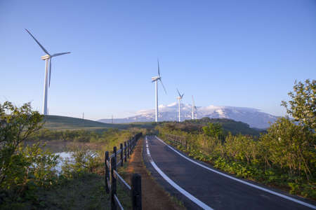 Wind turbines with a scenic snow-capped mountainの写真素材