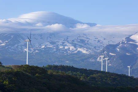 Wind turbines with a scenic snow-capped mountainの写真素材