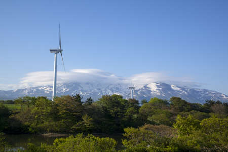 Wind turbines with a scenic snow-capped mountainの写真素材