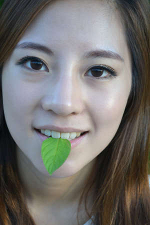 Beautiful young asian women with a leaf in mouth の写真素材