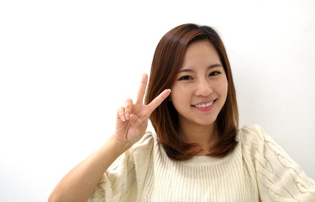 Smiling Young Woman Two Finger Peace Sign Hand Gestureの写真素材
