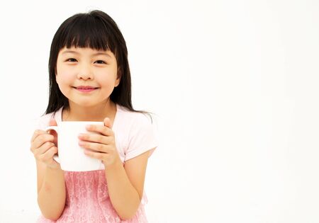 Beautiful little asian girl with mug isolated on white backgroundの写真素材