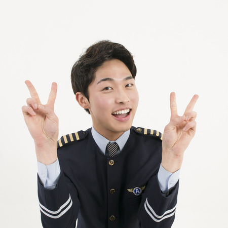 Smiling Asian Airline Pilot With Two Finger Peace Sign Hand Gestureの写真素材