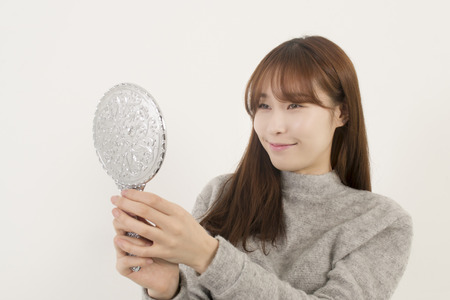 Pretty woman looking at herself in the mirrorの写真素材