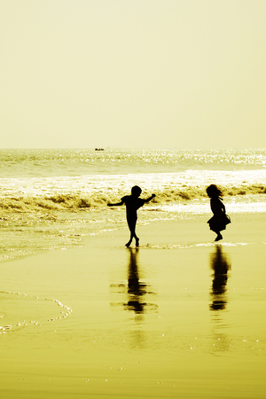 Two children dancing on the beach at sunset, Indiaの写真素材