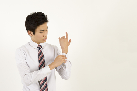 Asian young businessman fastening buttons on shirt sleeveの写真素材