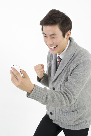 Very happy young asian man with smart phoneの写真素材