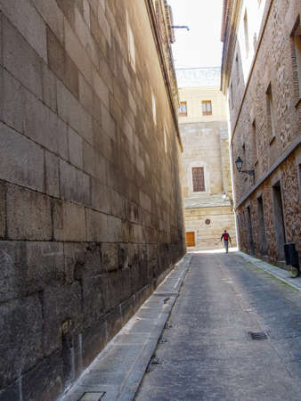 A man holding a skateboard walking down the alley in Toledo, Spainの写真素材