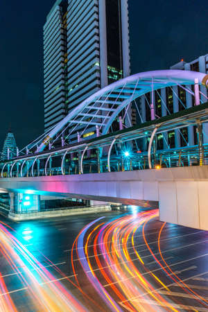 Light trails from the vehicles at the intersection with a walk-over pedestrain bridgeの写真素材