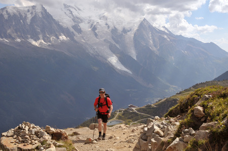 View of Alps mountains and a tourist hiking on a footpath.の写真素材