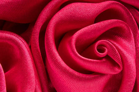Close up of shiny red fabric rose shaped flower.の写真素材
