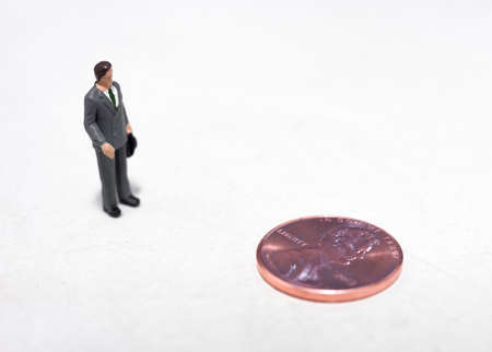 Small plastic people looking at a pennyの写真素材