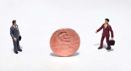 Small plastic people looking at a pennyの写真素材
