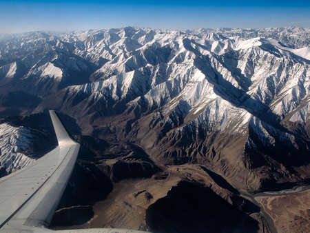 Airplane window view showing wing of plane flying over clouds and Rocky Mountains.の写真素材