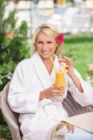 Having a good time. Attractive young women in bathrobe drinking cocktail while sitting at the tableの写真素材