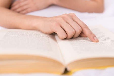 Reading a book. Close-up of finger pointing the bookの写真素材
