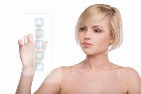 Girl from the future. Beautiful naked blond hair woman pushing the transparent buttons while isolated on whiteの写真素材