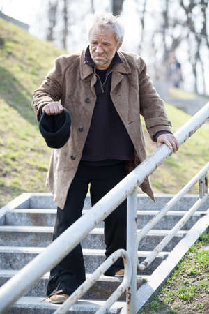 Homeless. Depressed man in dirty wear walking down the stairsの写真素材
